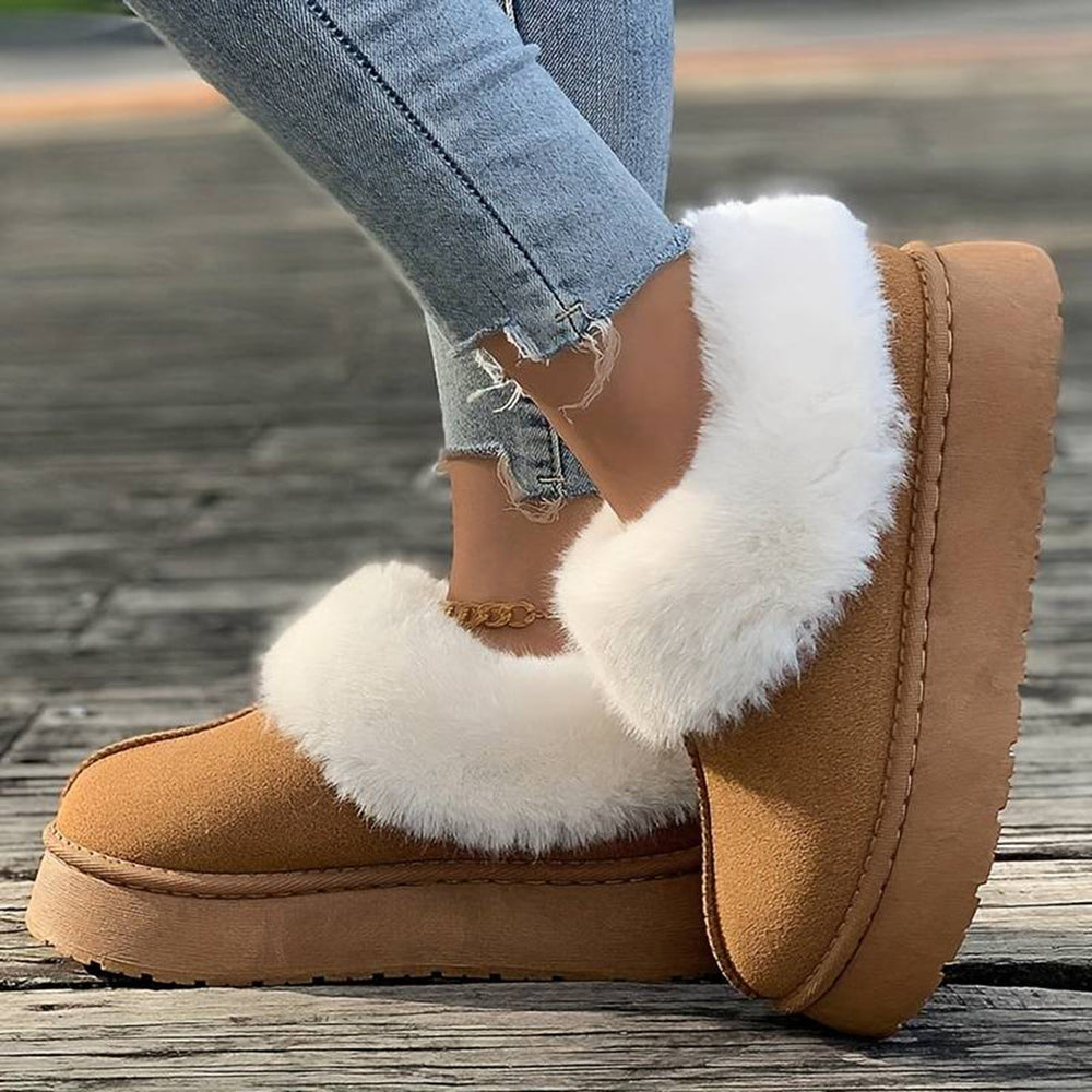 Bruine suède pantoffels met witte bontvoering, gedragen door persoon in gescheurde jeans. Comfortabele wintermode, warme damespantoffels.
