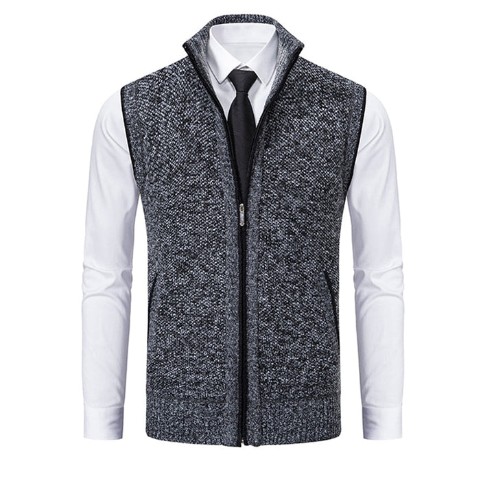 Donkergrijs gebreid herenvest met ritssluiting, gedragen over een witte overhemd en zwarte stropdas. Stijlvolle herenkleding, casual chic.