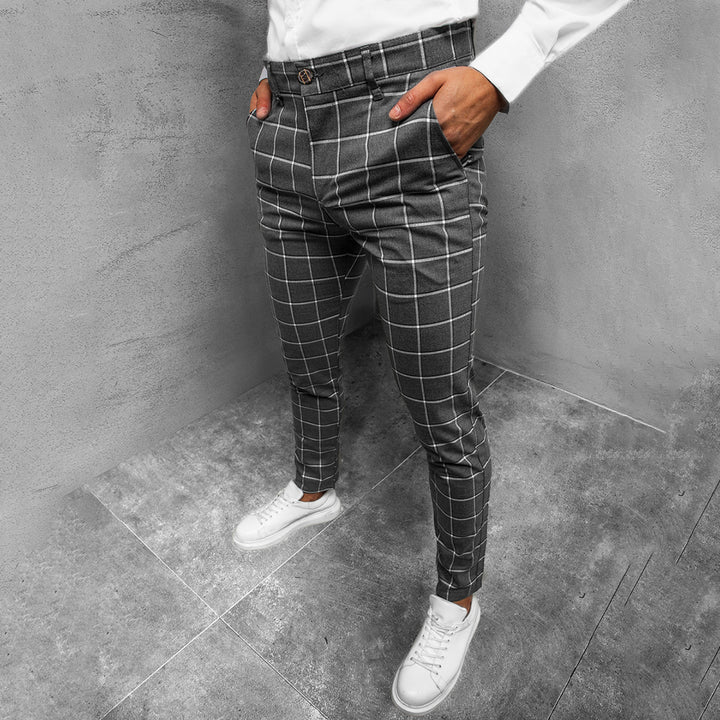 Donkergrijze geruite broek voor heren, slank gesneden, gedragen met witte sneakers en een wit overhemd. Stijlvolle moderne herenkleding.