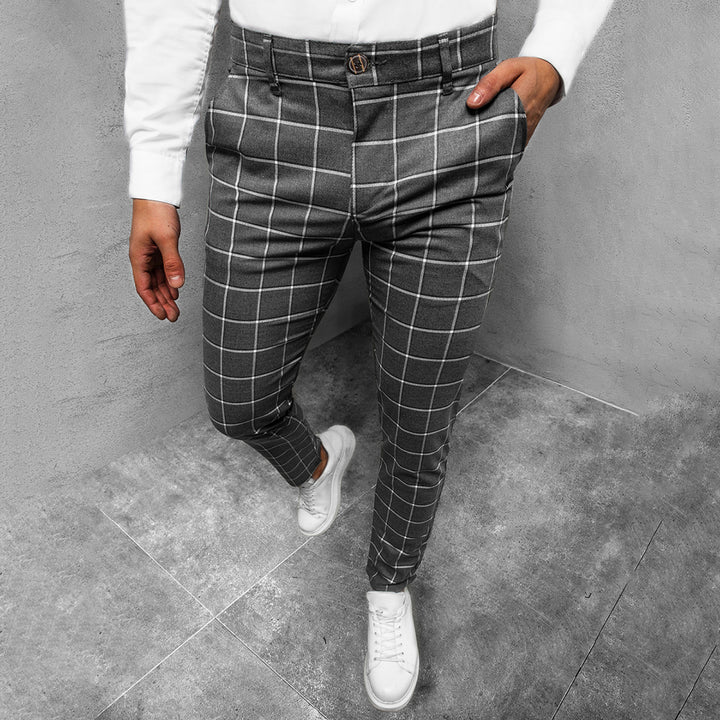 Donkergrijze geruite broek voor heren, stijlvolle slim fit pasvorm, gecombineerd met witte sneakers en een wit overhemd. Perfect voor casual en zakelijke looks.