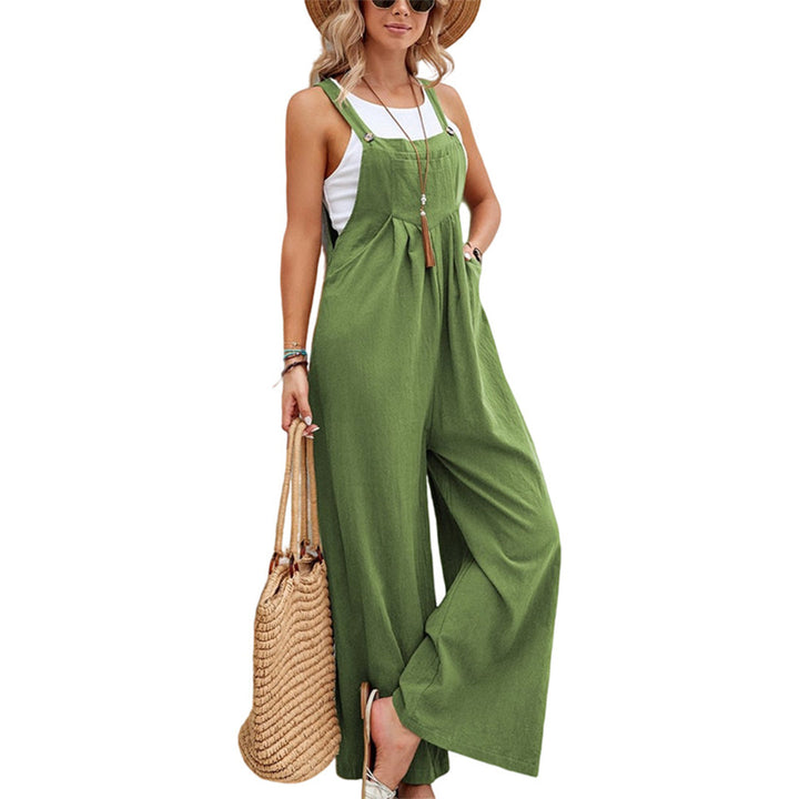 Vrouw in groene jumpsuit met brede pijpen, strohoed en rieten tas. Zomermode, casual outfit, trendy dameskleding.