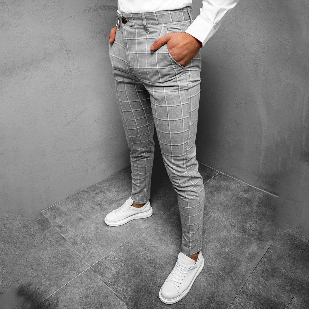 Grijze geruite herenbroek, slim fit, gedragen met witte sneakers en een wit overhemd. Stijlvolle zakelijke casual outfit voor mannen.