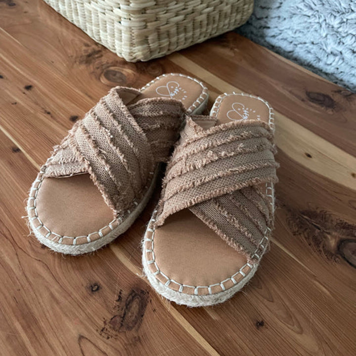 Bruine geweven espadrilles met gevlochten bandjes op houten vloer, zomerschoenen voor dames, casual en comfortabel, perfect voor strandvakanties.