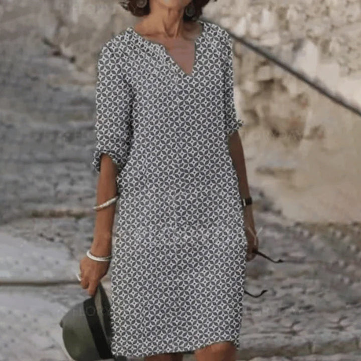 Grijze damesjurk met geometrisch patroon, driekwart mouwen en V-hals, ideaal voor casual zomeroutfits. Comfortabele en stijlvolle mode.