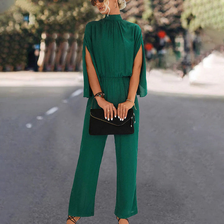 Groene jumpsuit met wijde pijpen en cape-mouwen, gedragen door een vrouw op straat. Modieuze dameskleding, ideaal voor casual en chique gelegenheden.