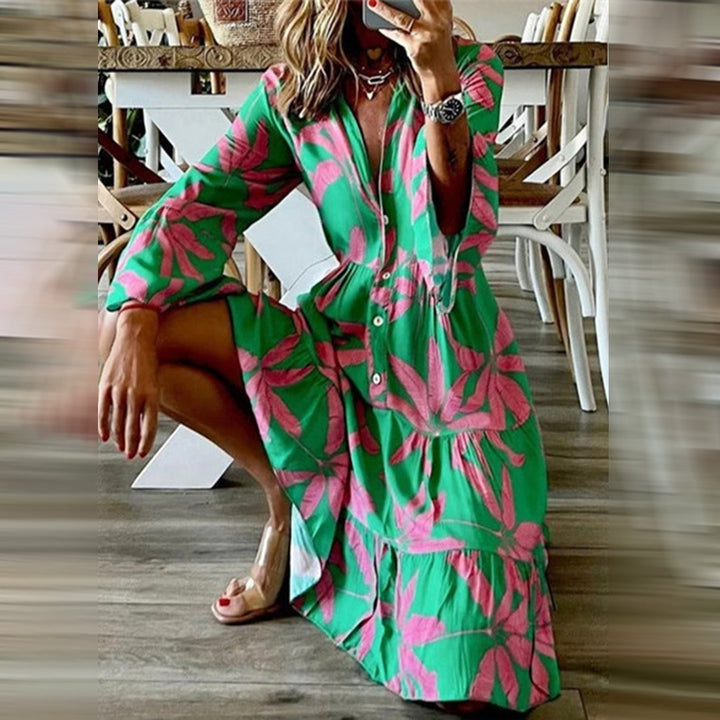 Vrouw in groene jurk met roze bloemenprint, zittend op houten vloer. Trendy zomerjurk, lange mouwen, knopen, casual mode, bohemian stijl.