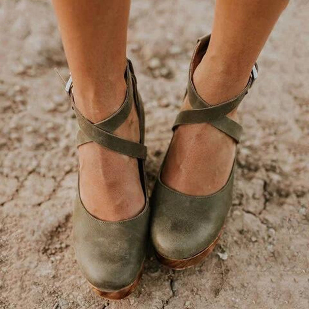 Groene leren damesschoenen met kruisbanden, comfortabele hak, op een ruwe ondergrond. Perfect voor casual en modieuze outfits.