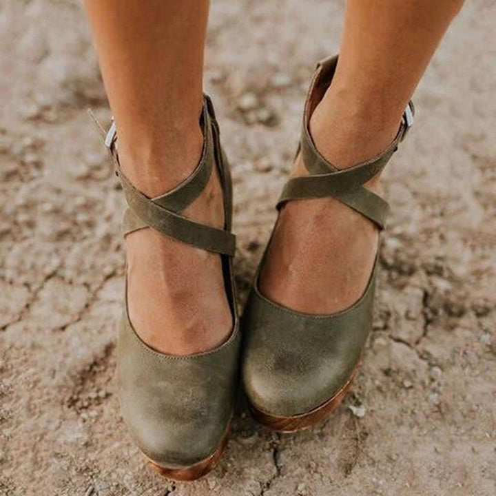Groene leren damesschoenen met kruisbanden, comfortabele hak, op een ruwe ondergrond. Perfect voor casual en modieuze outfits.