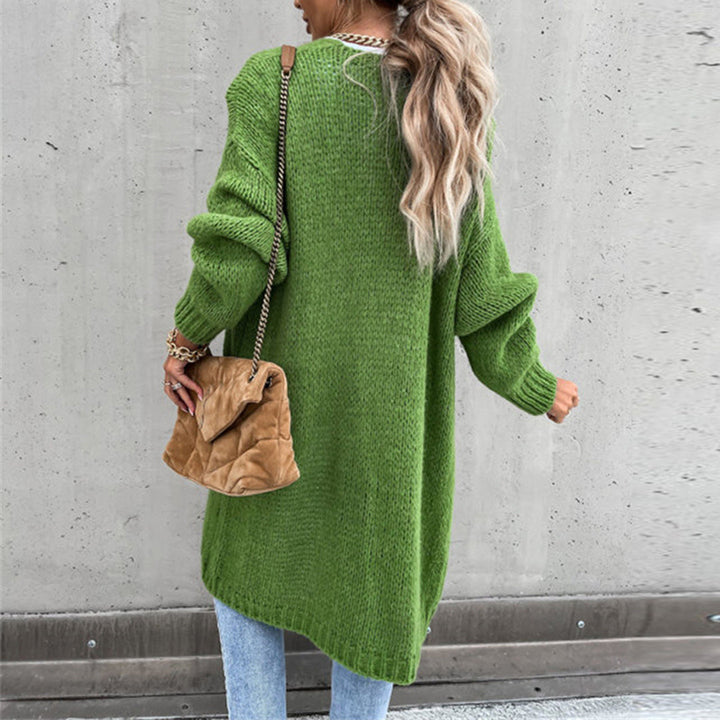 Vrouw in groene oversized trui met lange mouwen, draagt een bruine tas, casual mode, herfstkleding, trendy streetwear, betonnen achtergrond.