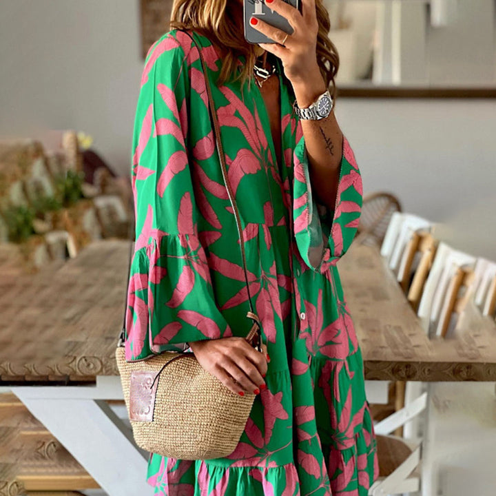 Vrouw in groene jurk met roze bladpatroon, houdt een rieten handtas vast. Trendy zomeroutfit, casual stijl, modeaccessoires, binnenomgeving.