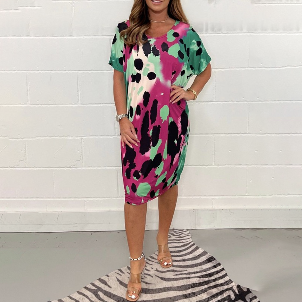 Vrouw in kleurrijke jurk met groene, roze en zwarte vlekken, staand op zebraprint tapijt. Trendy zomerjurk, casual mode, dameskleding.