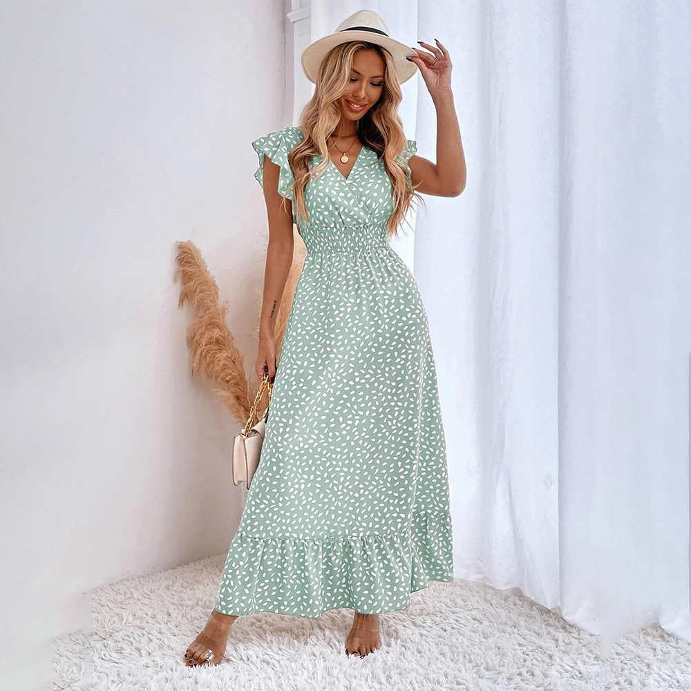 Vrouw in groene zomerjurk met witte stippen, rieten hoed en handtas, poseert op witte achtergrond. Perfecte outfit voor zomermode en strandstijl.