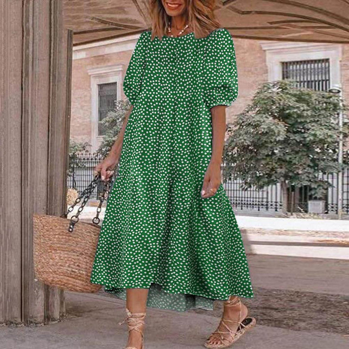 Vrouw in groene jurk met witte stippen, draagt een rieten tas en sandalen. Zomerse outfit, casual mode, stedelijke achtergrond.