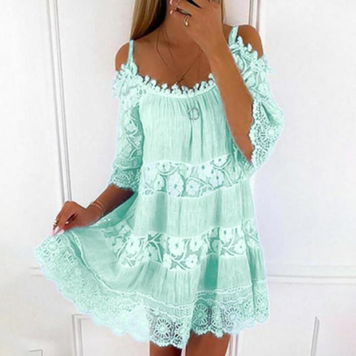 Vrouw in mintgroene kanten zomerjurk met bloemenpatroon, off-shoulder ontwerp en korte mouwen. Perfect voor strandmode en zomerse outfits.