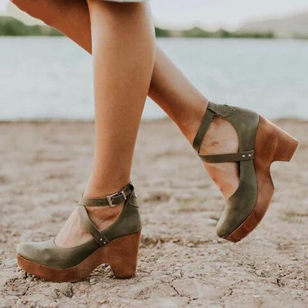 Groene dameshakken met houten plateauzool, kruisbandjes en gesp, gedragen op een strand. Stijlvolle zomerschoenen voor casual en elegante outfits.