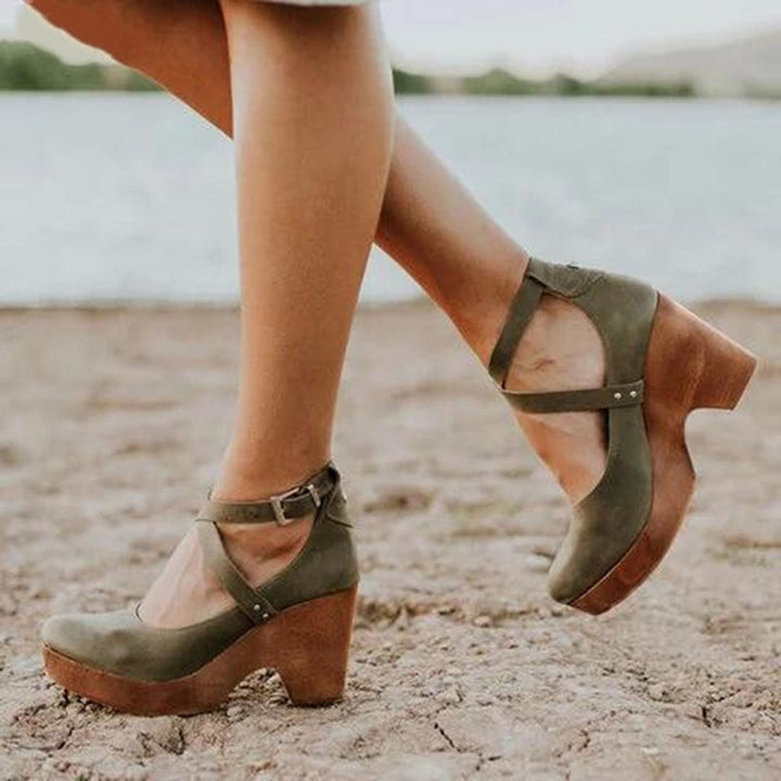 Groene dameshakken met houten plateauzool, kruisbandjes en gesp, gedragen op een strand. Stijlvolle zomerschoenen voor casual en elegante outfits.