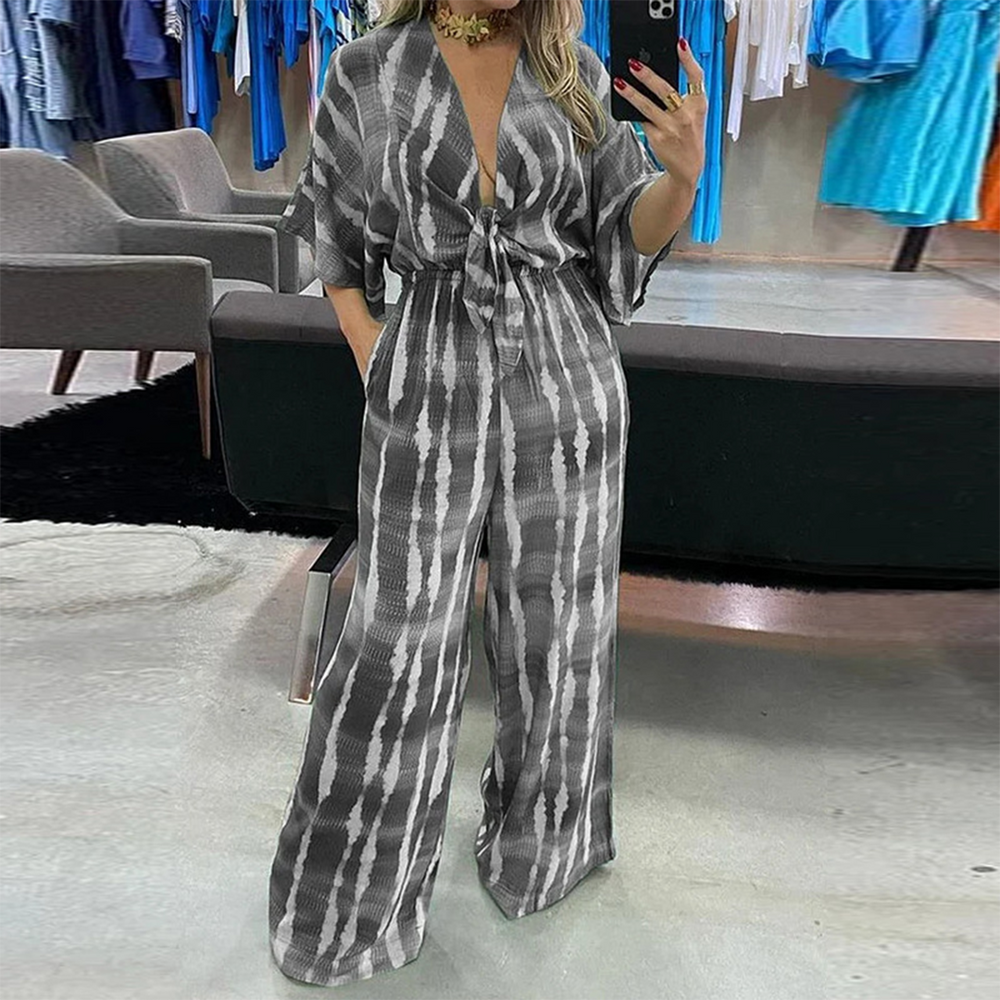 Grijze jumpsuit met wijde pijpen en abstract patroon, gedragen door vrouw in moderne kledingwinkel. Trendy damesmode, comfortabele pasvorm.