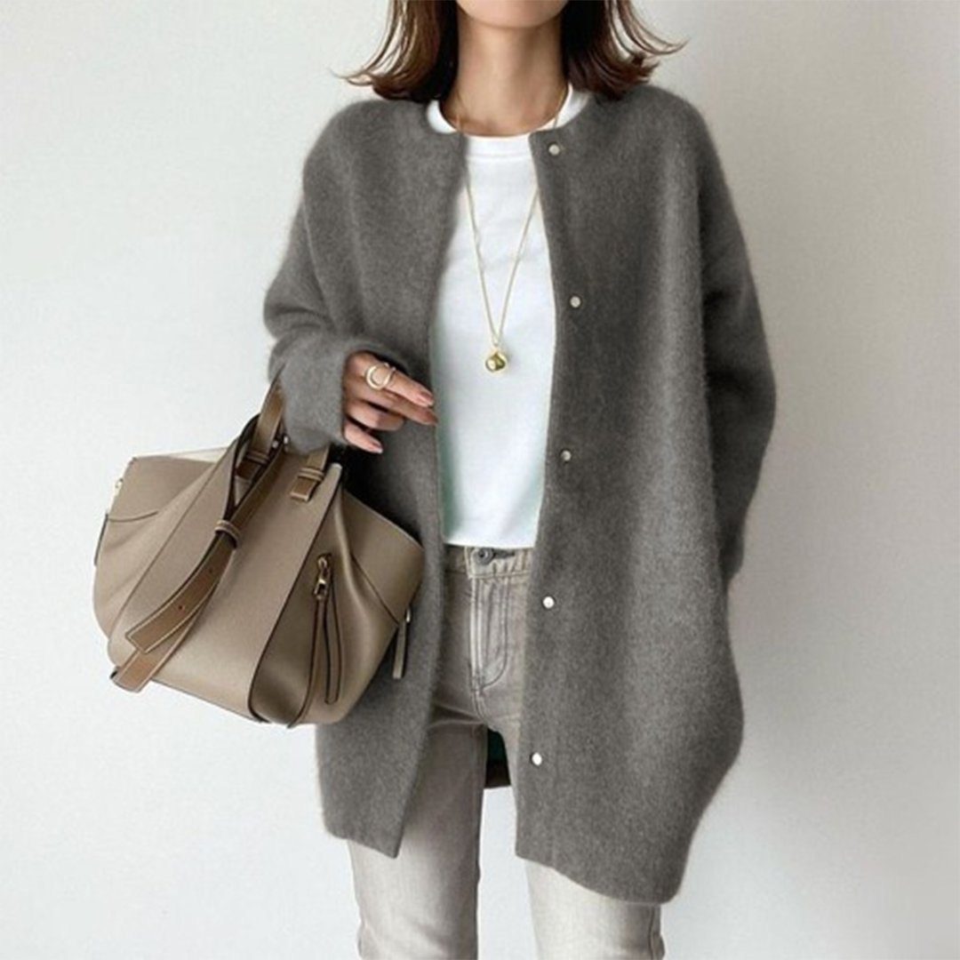 Grijze wollen damesjas met knopen, gecombineerd met een beige handtas en casual witte top. Modieuze herfstkleding voor dames.
