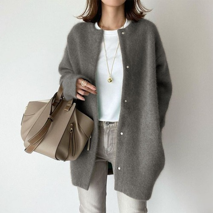 Grijze wollen damesjas met knopen, gecombineerd met een beige handtas en casual witte top. Modieuze herfstkleding voor dames.