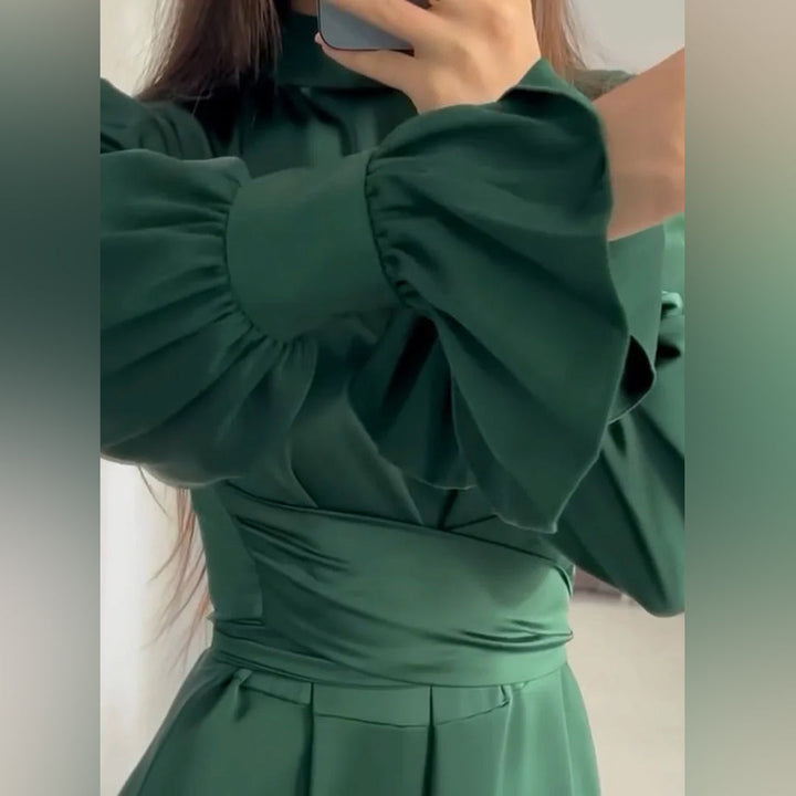 Groene lange damesjurk met pofmouwen, elegante satijnen stof, modieuze uitstraling. Perfect voor formele gelegenheden en stijlvolle evenementen.