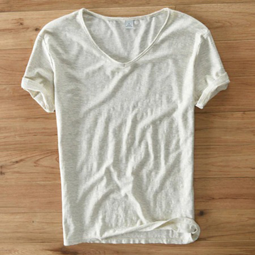 Crèmekleurig T-shirt van biologisch katoen, V-hals, korte mouwen, casual stijl, op houten vloer. Perfect voor duurzame mode en comfort.