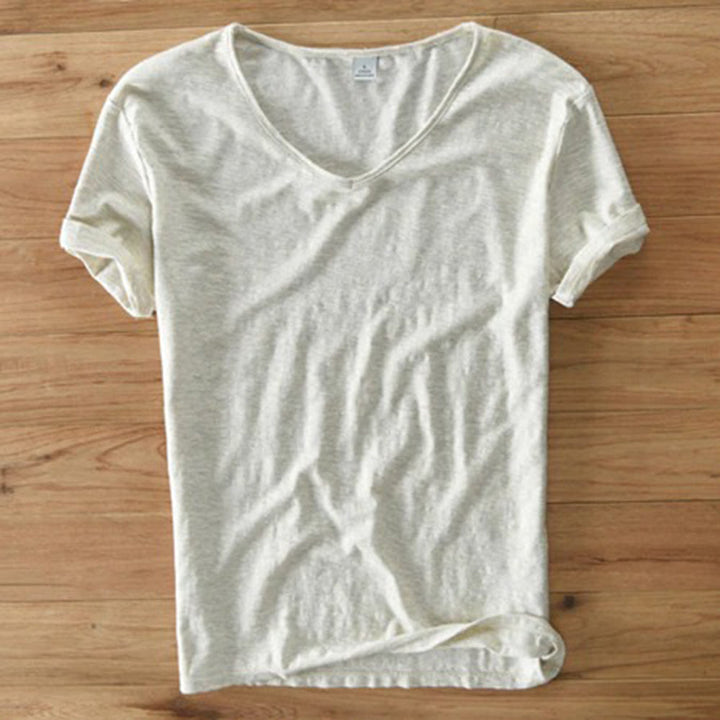 Crèmekleurig T-shirt van biologisch katoen, V-hals, korte mouwen, casual stijl, op houten vloer. Perfect voor duurzame mode en comfort.