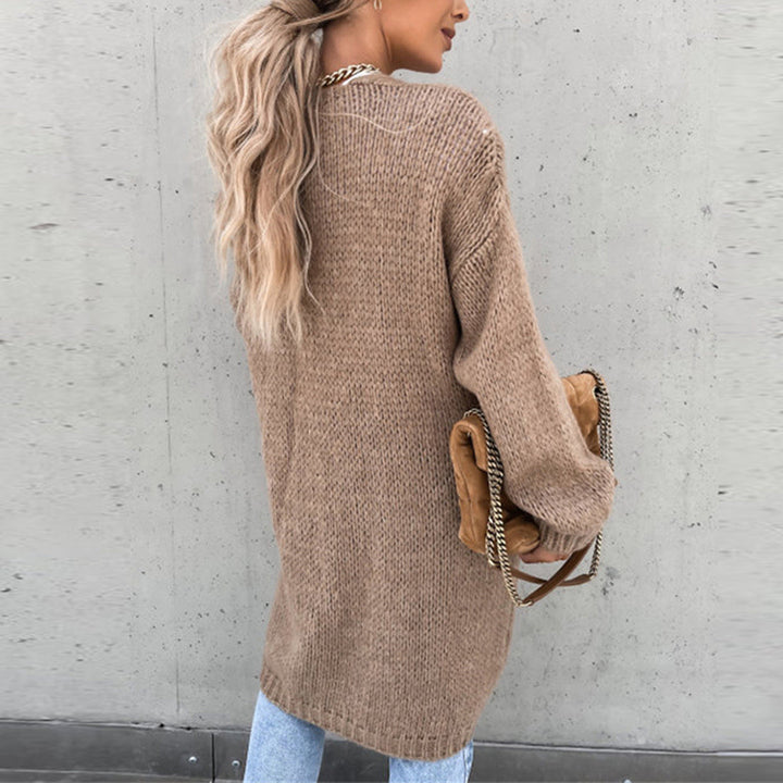 Vrouw in beige gebreide trui met lange mouwen, draagt een bruine tas met gouden ketting, casual mode, herfstkleding, trendy damesoutfit.