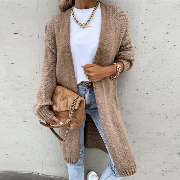 Vrouw in casual outfit met beige gebreid vest, witte T-shirt, blauwe jeans en bruine tas. Modieuze herfstlook, trendy dameskleding.