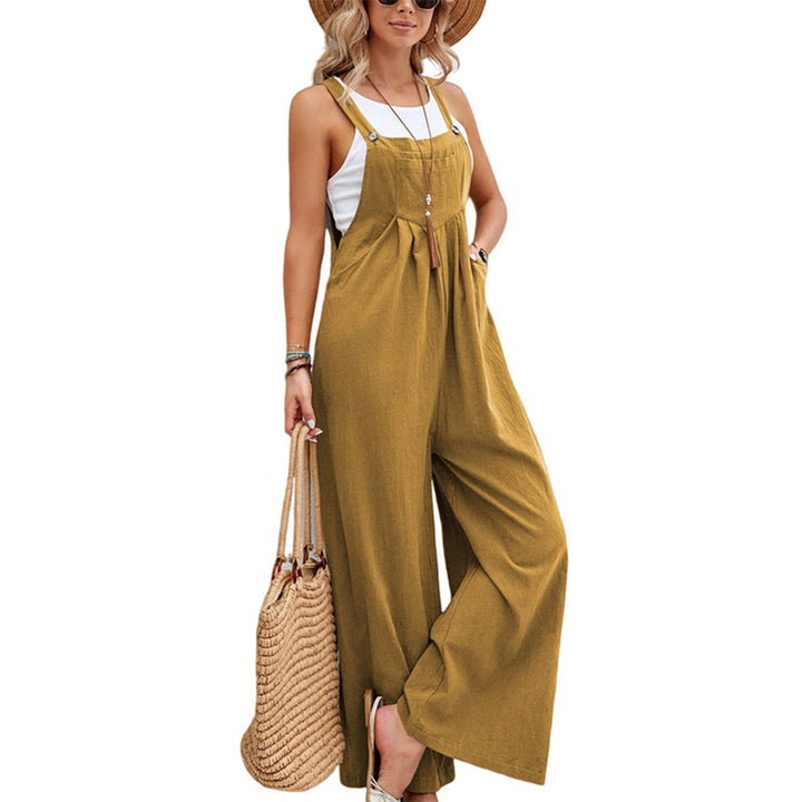 Vrouw in khaki jumpsuit met wijde pijpen, witte top en strohoed, draagt een gevlochten tas. Zomerse damesmode, casual en stijlvol.