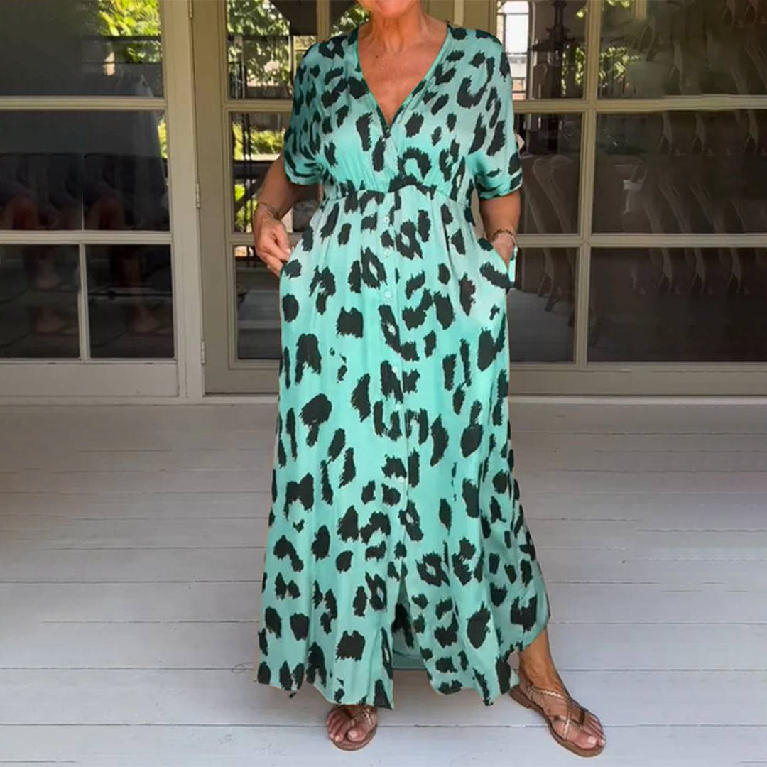 Vrouw in lange, groene jurk met zwart luipaardprint, staand op houten vloer. Zomerse mode, casual stijl, comfortabele pasvorm, trendy design.
