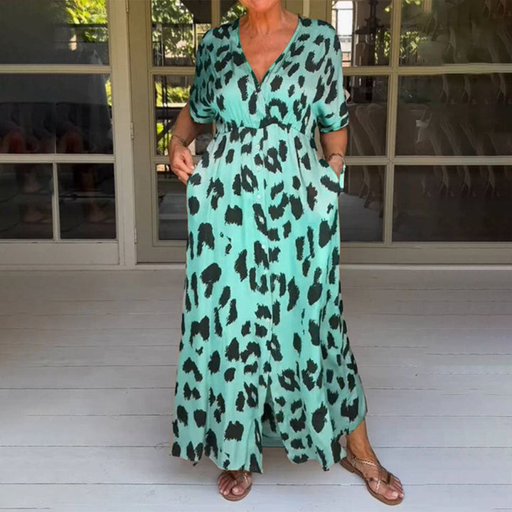 Vrouw in lange, groene jurk met zwart luipaardprint, staand op houten vloer. Zomerse mode, casual stijl, comfortabele pasvorm, trendy design.