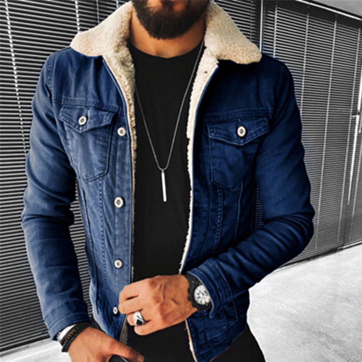 Man in blauwe spijkerjas met schapenvachtkraag, zwarte shirt en zilveren ketting. Modieuze herenkleding, casual stijl, denim jas.
