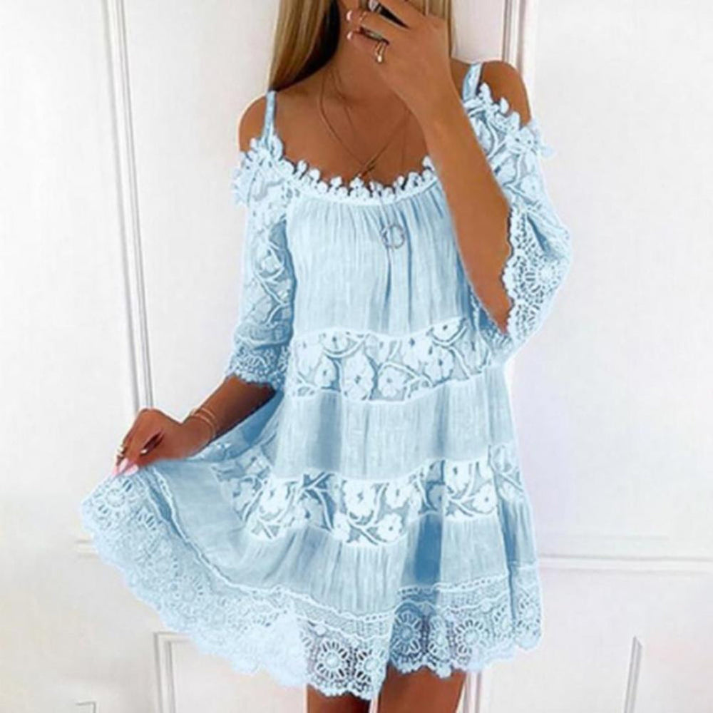 Vrouw in lichtblauwe kanten zomerjurk met schouderbandjes, bloemenpatroon en ruches, perfect voor casual en strandoutfits.