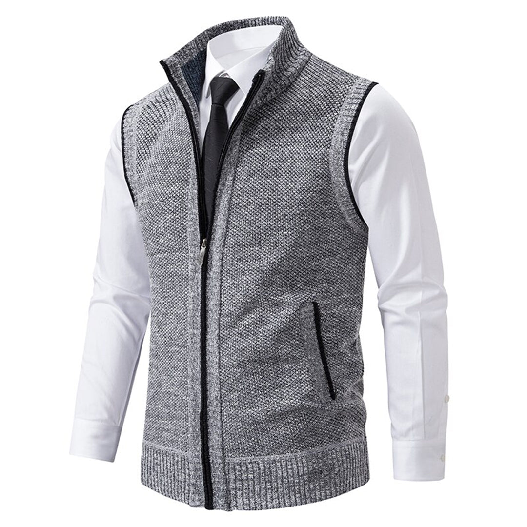 Grijze gebreide herenvest met ritssluiting, gedragen over een witte overhemd en zwarte stropdas. Stijlvolle casual mode voor heren.