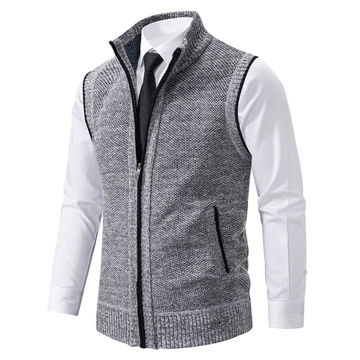 Grijze gebreide herenvest met ritssluiting, gedragen over een witte overhemd en zwarte stropdas. Stijlvolle casual mode voor heren.
