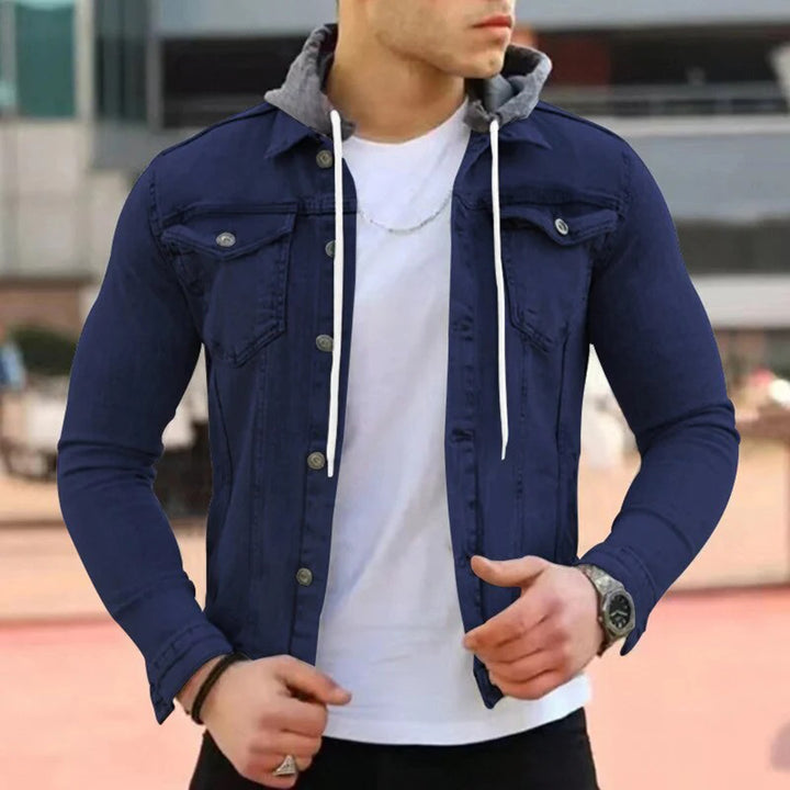 Man in een marineblauw denimjack met grijze capuchon, witte T-shirt en horloge. Stijlvolle herenkleding, casual mode, buitenkleding.