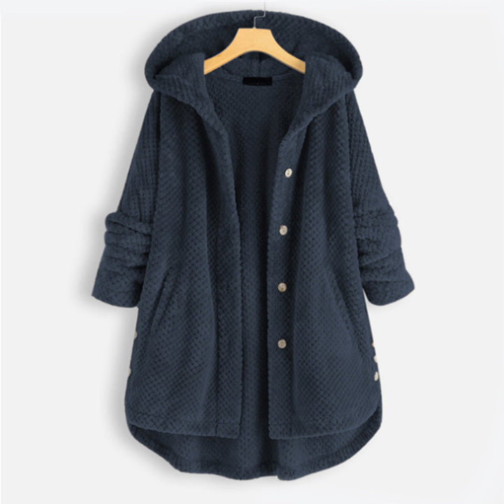Donkerblauwe fleecejas met capuchon, knopen en zakken, hangend aan een houten hanger. Comfortabele damesjas voor herfst en winter.