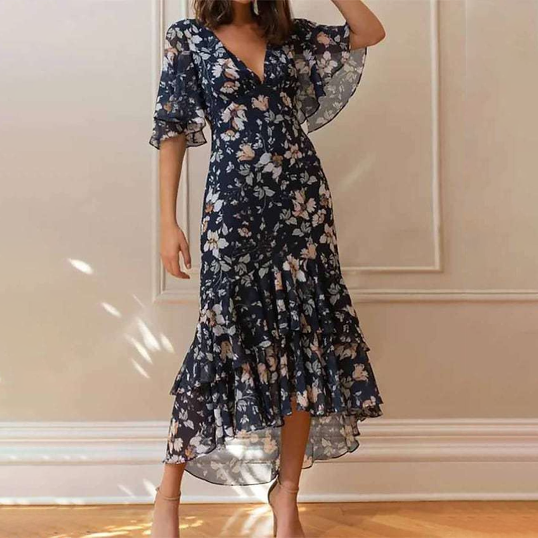 Vrouw in elegante marineblauwe bloemenjurk met V-hals en ruches, perfect voor zomerse gelegenheden. Stijlvolle damesmode, trendy jurk.
