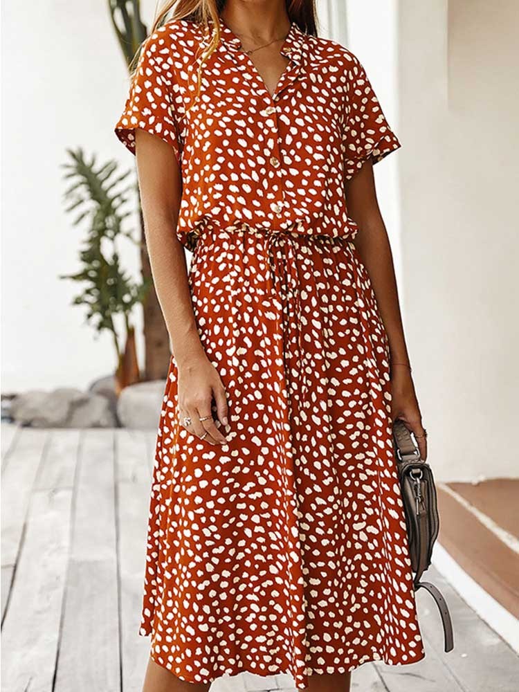 Oranje zomerjurk met witte stippen, korte mouwen en knoopsluiting. Perfect voor casual damesmode. Trendy en comfortabel ontwerp.