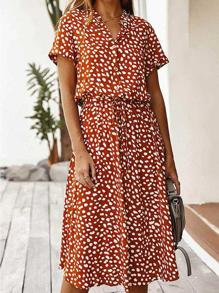 Oranje zomerjurk met witte stippen, korte mouwen en knoopsluiting. Perfect voor casual damesmode. Trendy en comfortabel ontwerp.