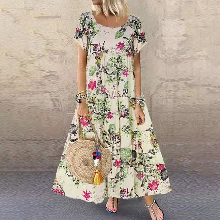 Vrouw in lange, bloemenjurk met korte mouwen en ronde hals, draagt een ronde rieten tas. Perfect voor zomermode en casual outfits.