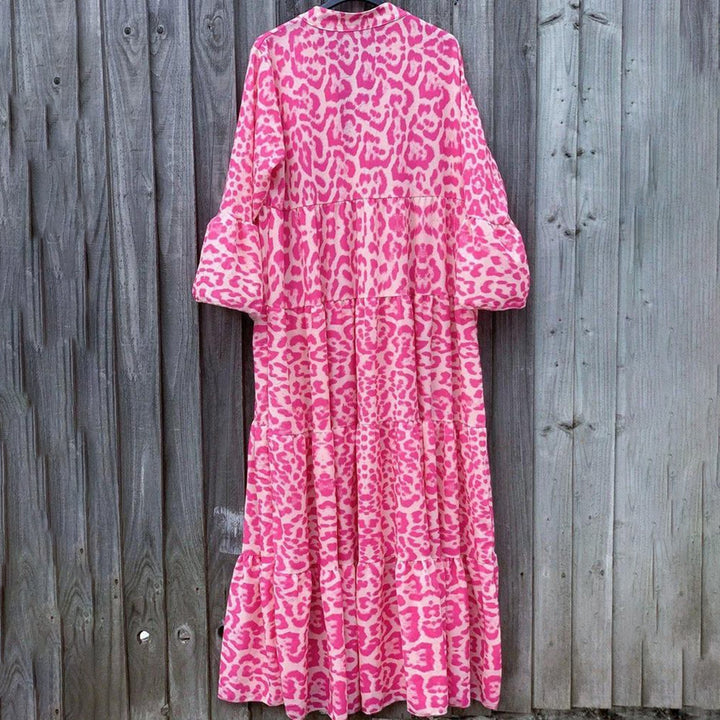 Roze luipaardprint maxi-jurk tegen houten achtergrond, lange mouwen, modetrend, opvallend ontwerp, dameskleding, bohemian stijl.