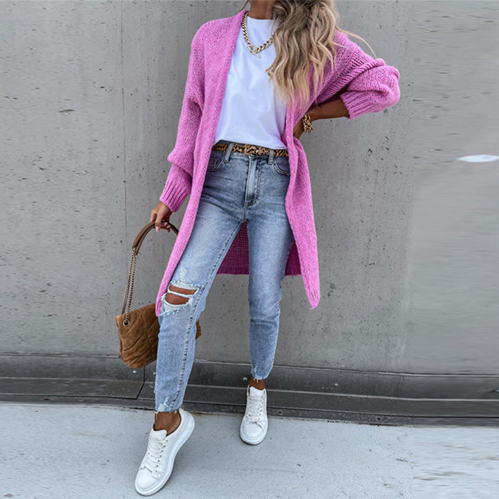 Vrouw in casual outfit met roze gebreid vest, witte sneakers en gescheurde jeans. Modieuze streetwear look, perfect voor lente en herfst.
