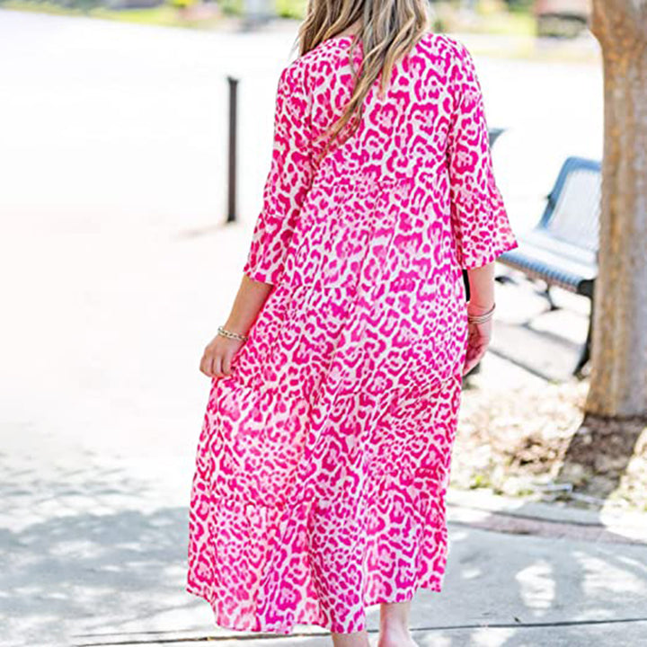 Vrouw in roze luipaardprint jurk, driekwart mouwen, buiten op zonnige dag. Trendy zomerjurk, casual mode, kleurrijke kledingstijl.