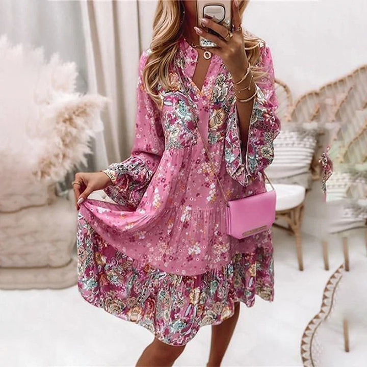 Vrouw in roze bloemenjurk met lange mouwen, houdt roze handtas vast. Trendy damesmode, boho-stijl, casual outfit voor lente/zomer.