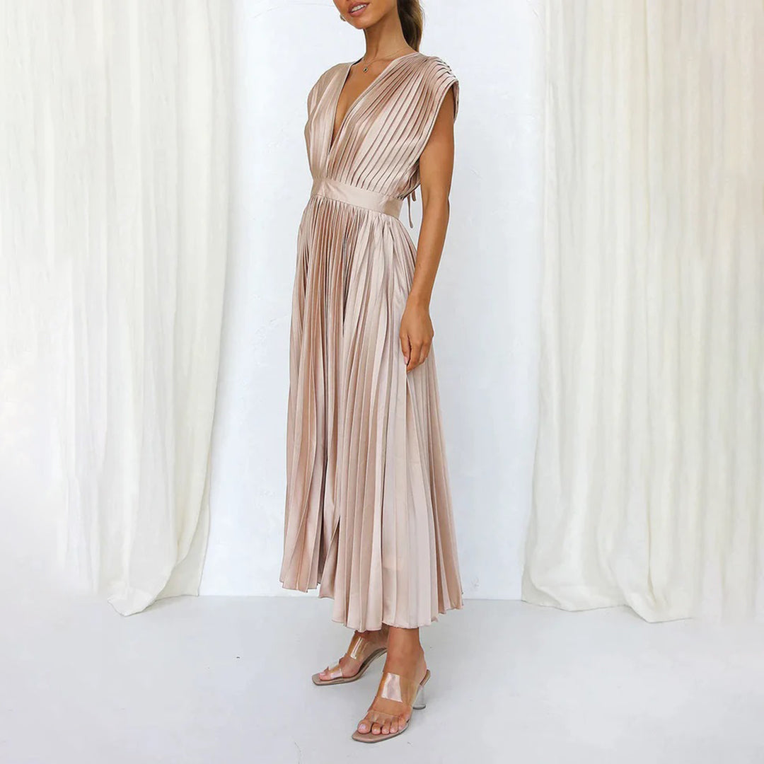 Vrouw in elegante roze geplooide jurk met diepe V-hals, staand voor witte gordijnen. Perfect voor avondkleding, bruiloften, galajurken.