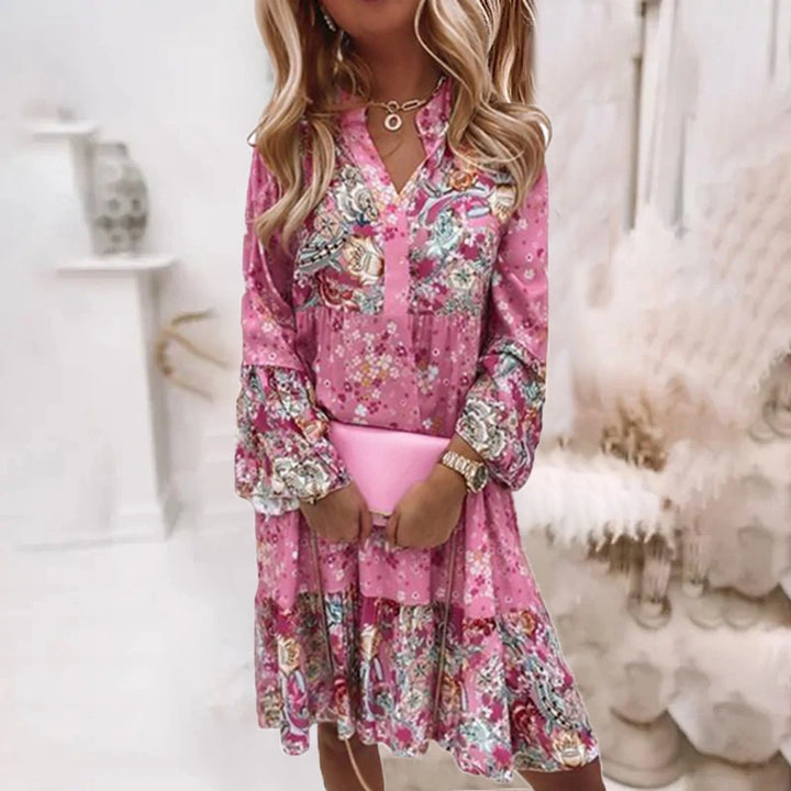 Vrouw in roze bloemenjurk met lange mouwen, houdt roze clutch vast. Trendy damesmode, bohemian stijl, casual chique outfit voor lente/zomer.