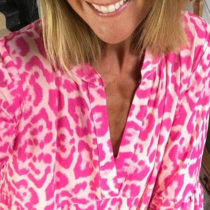 Vrouw in roze luipaardprint blouse, glimlachend. Modieuze dameskleding, trendy dierenprint, casual stijl, zomeroutfit.