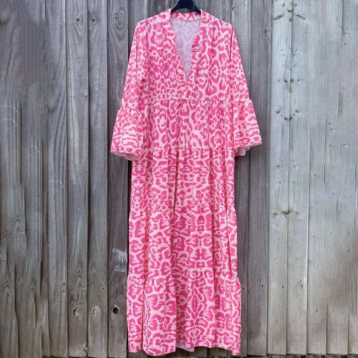 Roze maxi-jurk met luipaardprint, lange mouwen en V-hals, hangend voor een houten achtergrond. Trendy damesmode, bohemian stijl.