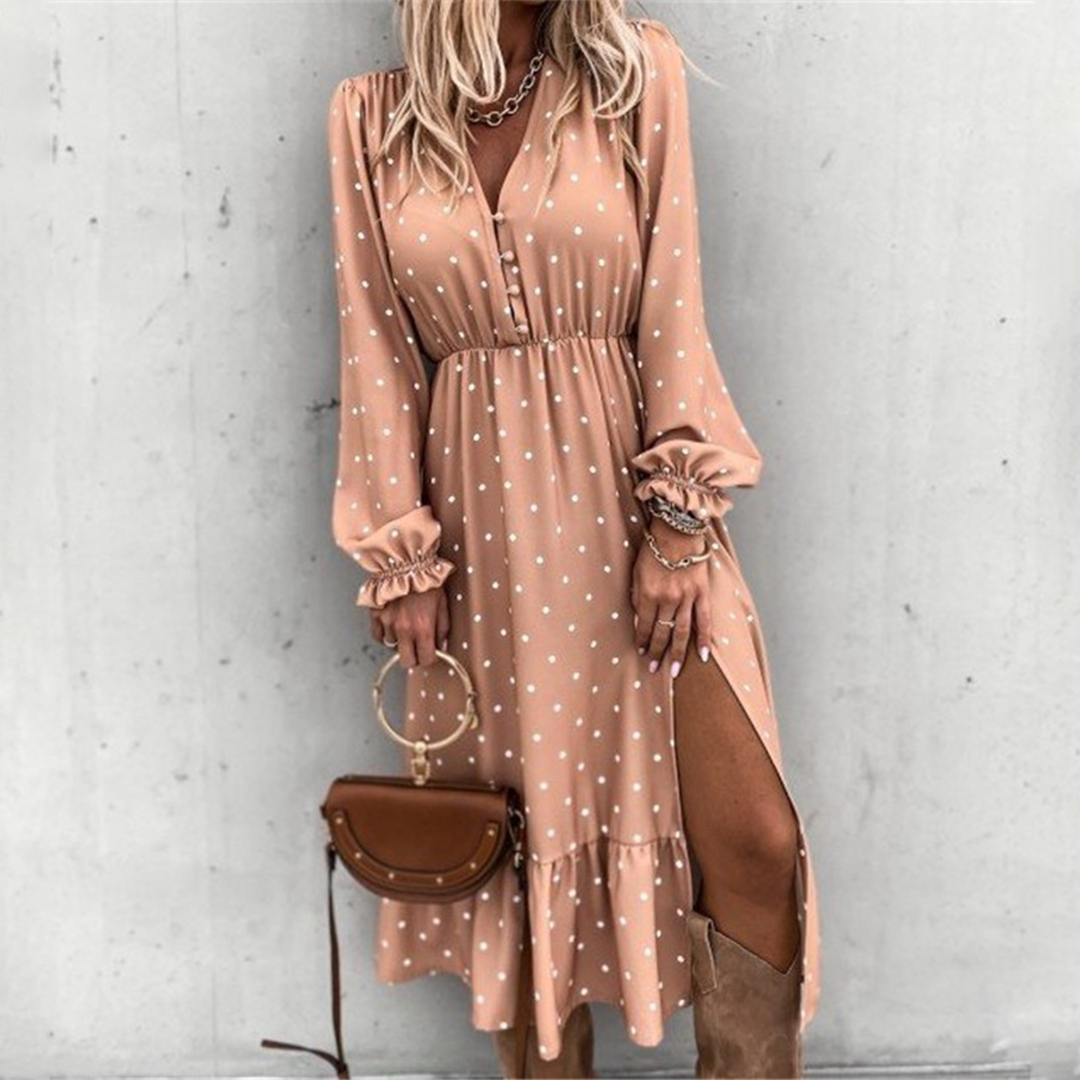 Vrouw in roze polkadot jurk met lange mouwen en hoge split, gecombineerd met bruine laarzen en tas. Trendy damesmode, elegante outfit.